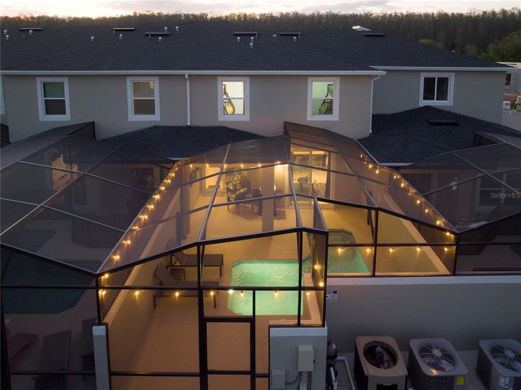 An aerial view of a screened-in pool patio attached to the back of a house — 2967 PENELOPE LOOP, KISSIMMEE, FL