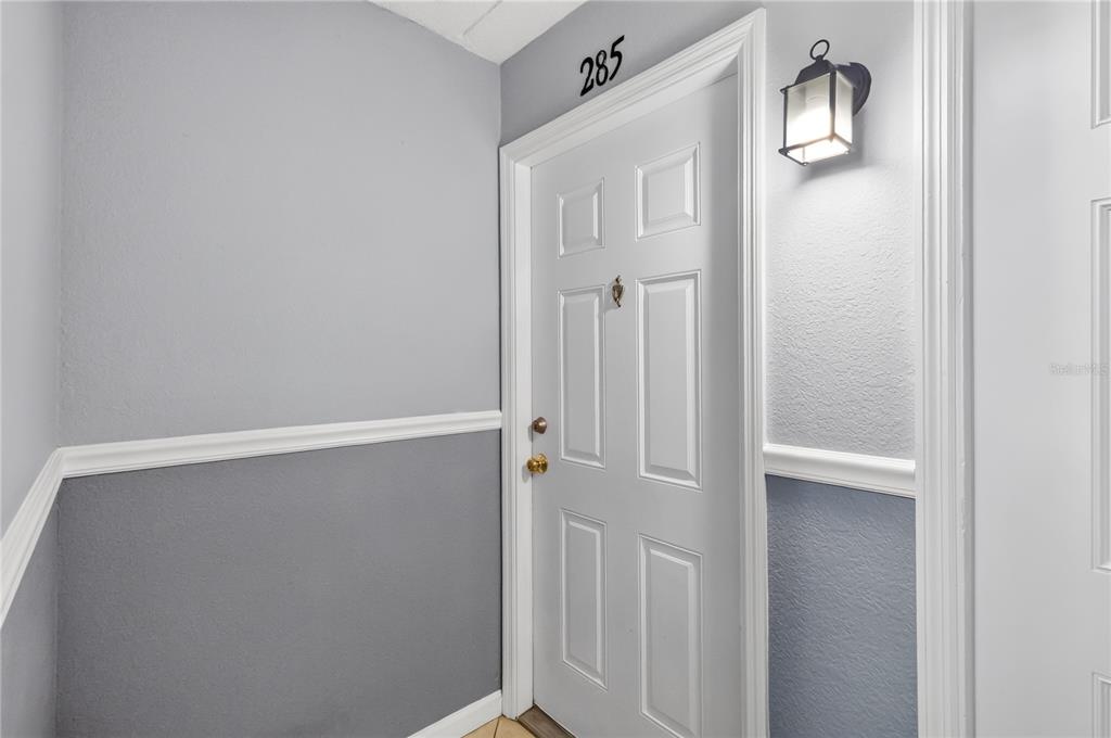 A white front door labeled 285 is set in a gray wall with white trim — 285 LEWFIELD CIRCLE UNIT 285, WINTER PARK, FL