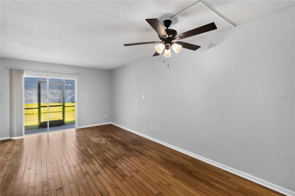 A living room with light gray walls, hardwood flooring, a ceiling fan, and sliding glass doors — 285 LEWFIELD CIRCLE UNIT 285, WINTER PARK, FL