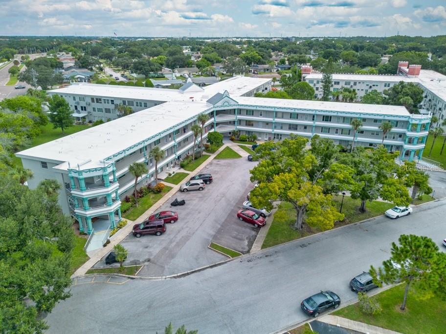 An aerial view of a multi-story apartment building with a parking lot and surrounding trees — 2370 JAMAICAN STREET UNIT 30, CLEARWATER, FL