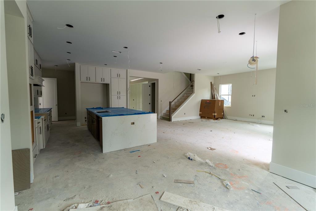 An unfinished kitchen and living area features a large center island and a staircase — 4906 W ESTRELLA STREET, TAMPA, FL