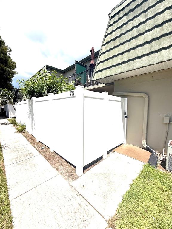 A white vinyl privacy fence encloses a patio area next to a building with siding — 1799 N HIGHLAND AVENUE UNIT 75, CLEARWATER, FL