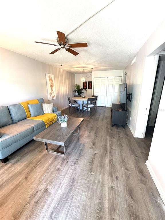 A living and dining room area features wood-look flooring, a gray sofa, and a round table — 1799 N HIGHLAND AVENUE UNIT 75, CLEARWATER, FL