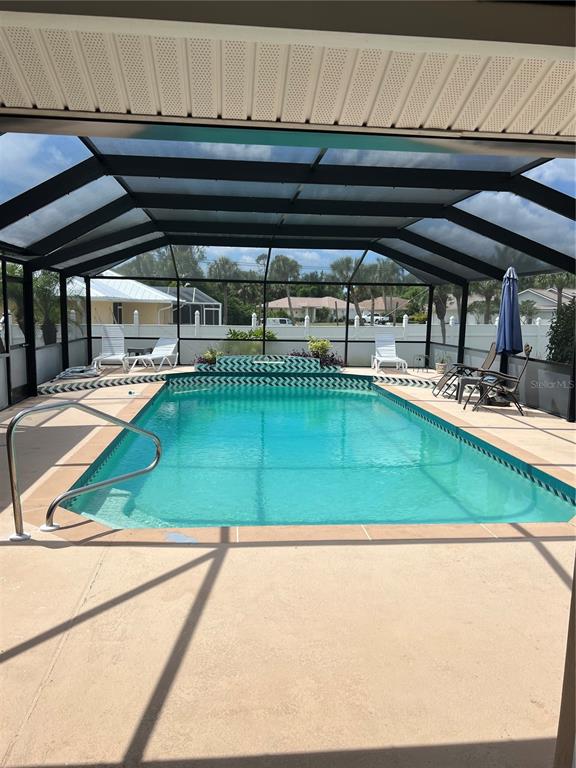 A rectangular swimming pool is enclosed within a screened-in patio area with lounge chairs — 3645 SLAYTON AVENUE, NORTH PORT, FL