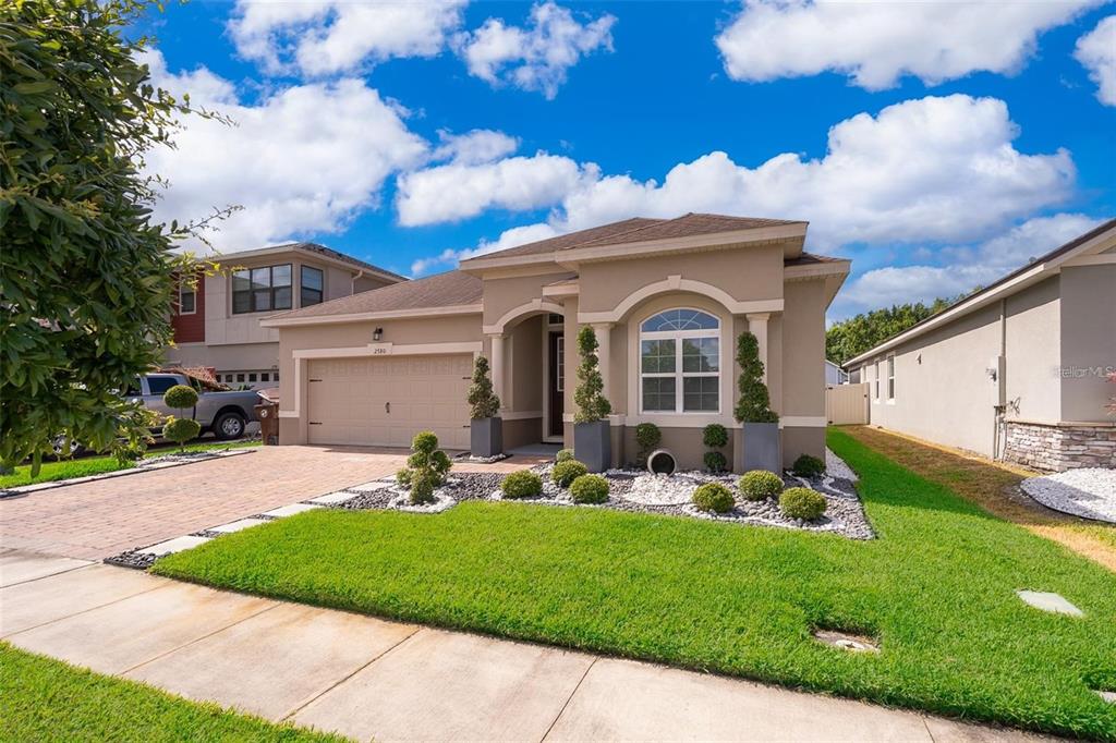 A single-story suburban house with a tan stucco exterior, a two-car garage, and landscaped yard — 2780 AVIAN LOOP, KISSIMMEE, FL