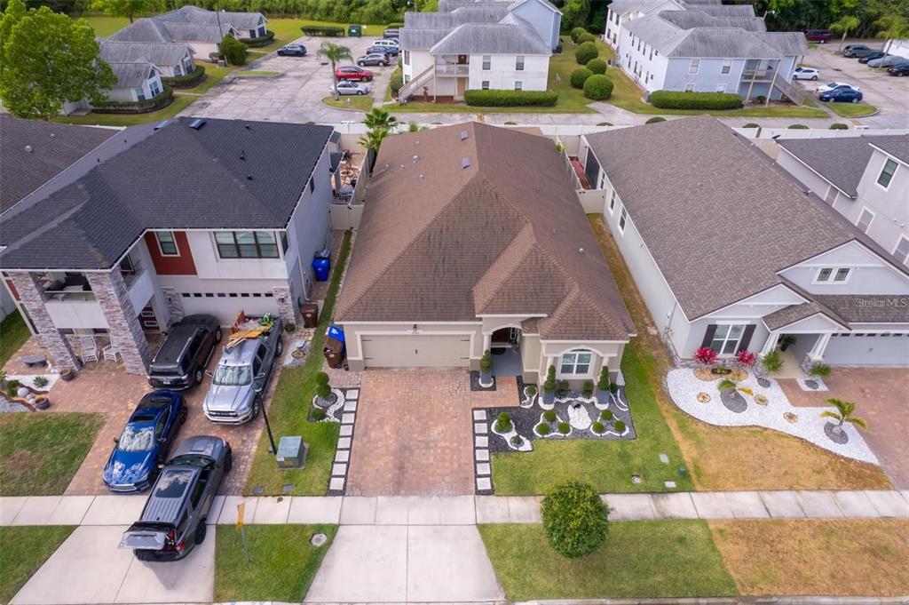 An aerial view shows three suburban houses with paved driveways and surrounding landscaping — 2780 AVIAN LOOP, KISSIMMEE, FL