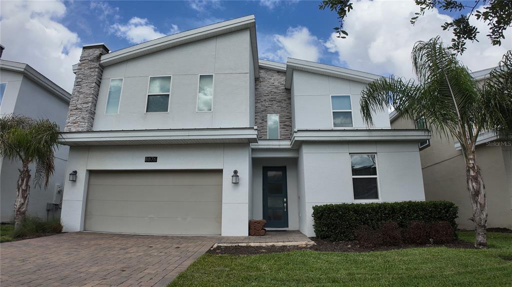 A two-story house with a stone-accented chimney, a two-car garage, and a paved driveway — 8876 CABOT CLIFFS DRIVE, DAVENPORT, FL