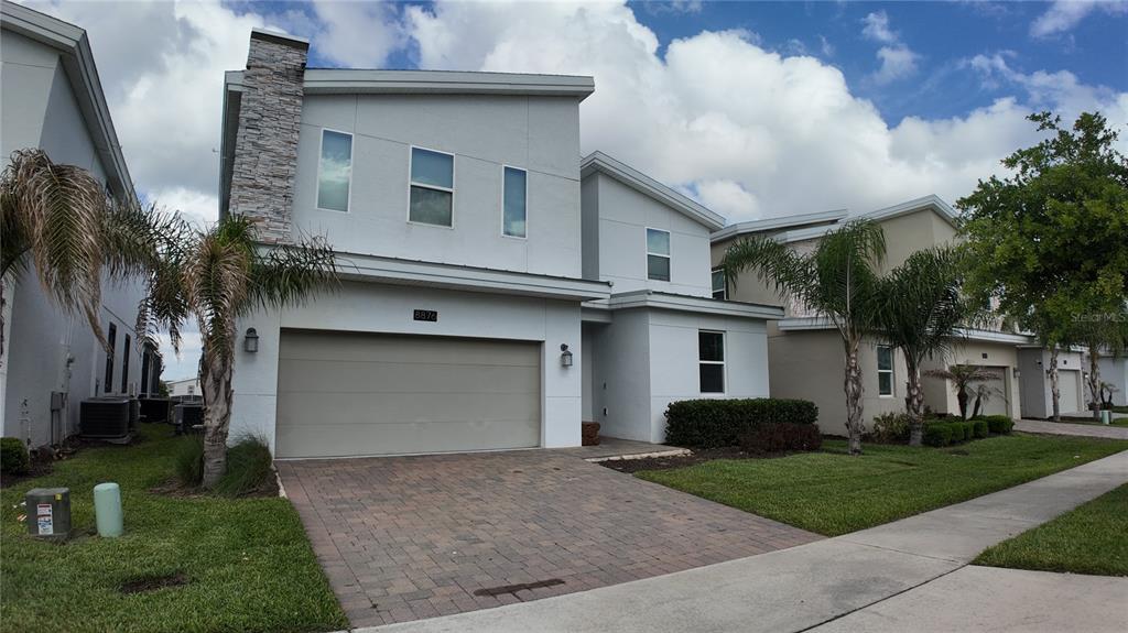 A two-story house with a stone-accented chimney, a two-car garage, and a paved driveway — 8876 CABOT CLIFFS DRIVE, DAVENPORT, FL
