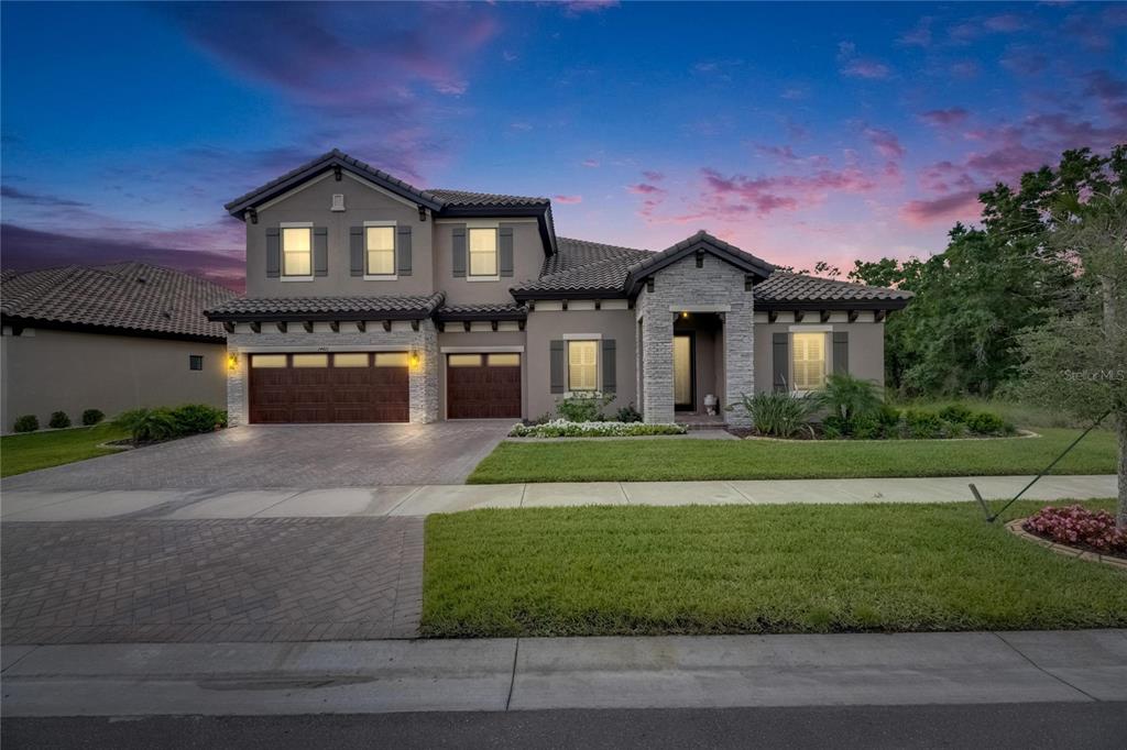 A two-story house with a gray stucco exterior, stone accents, and a paved driveway — 14421 SWISS BRIDGE DRIVE, LITHIA, FL