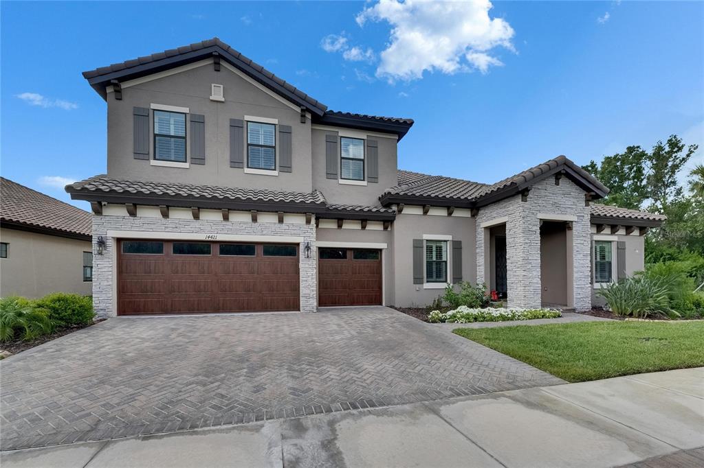 A stone-faced entryway with a glass-paneled door, brick walkway, and landscaped front yard — 14421 SWISS BRIDGE DRIVE, LITHIA, FL