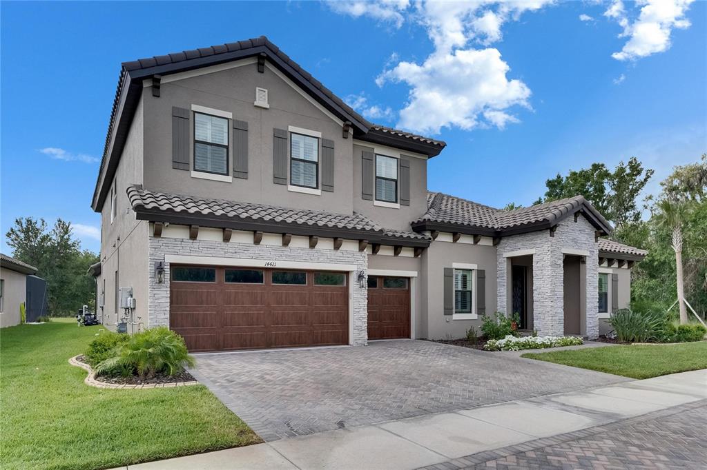 A two-story house with a stone facade, tile roof, and a three-car garage — 14421 SWISS BRIDGE DRIVE, LITHIA, FL