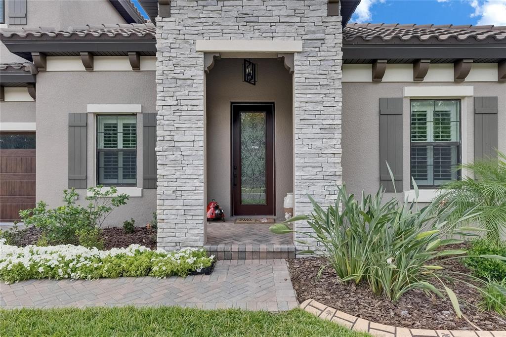 A two-story suburban house features a stone-accented facade, a tile roof, and a paved driveway — 14421 SWISS BRIDGE DRIVE, LITHIA, FL