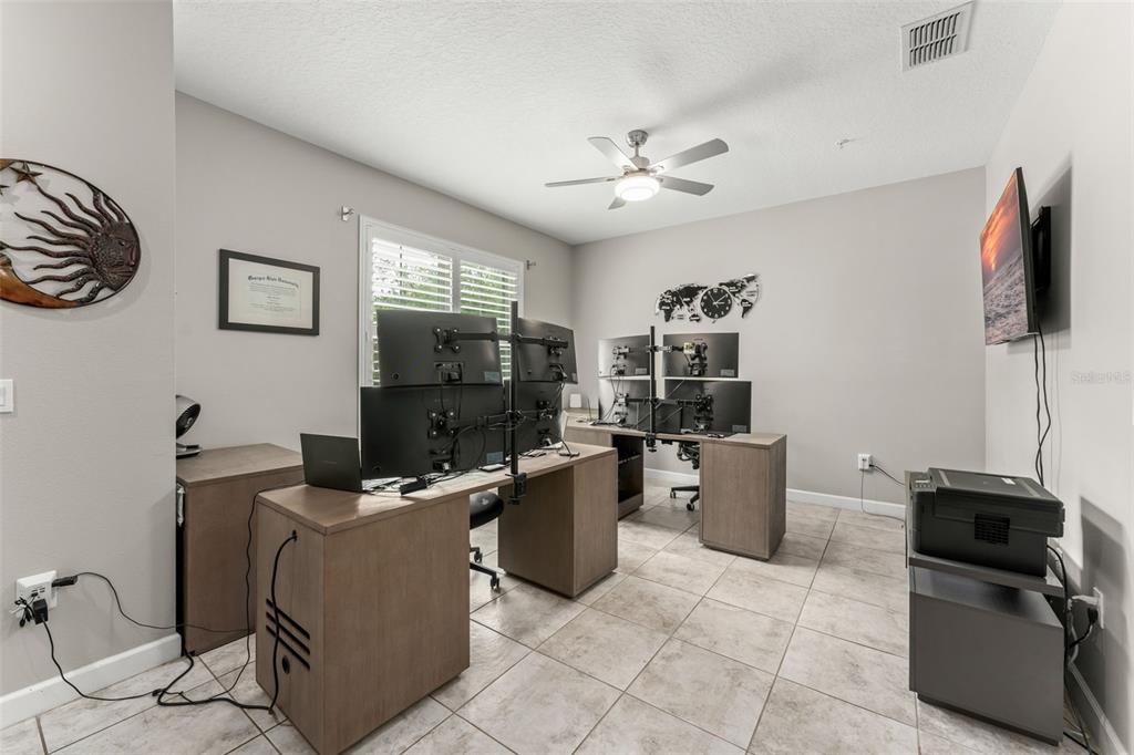 A home office features tile flooring, a desk with multiple monitors, and a staircase — 1457 LAKE GEORGE DRIVE UNIT 1457, LAKE MARY, FL