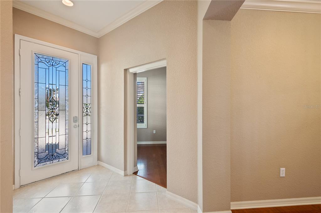 An entryway features a decorative glass front door, tiled flooring, and a doorway to another room — 2464 LAUREL GLEN DRIVE, LAKELAND, FL
