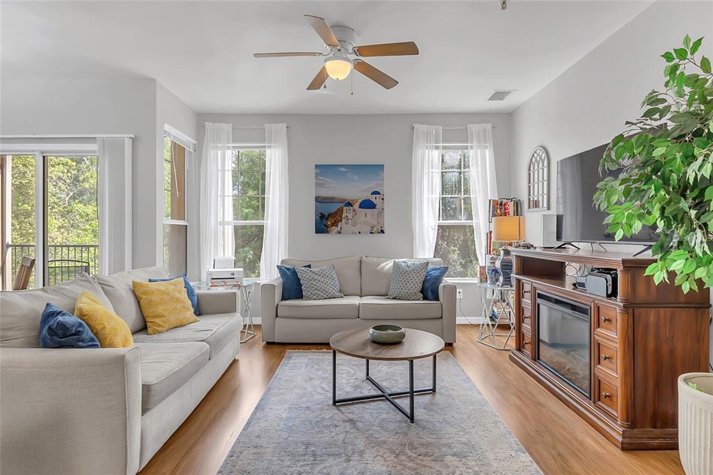 A living room features two gray sofas, a wood coffee table, and a fireplace console — 1995 ERVING CIRCLE UNIT 208, OCOEE, FL