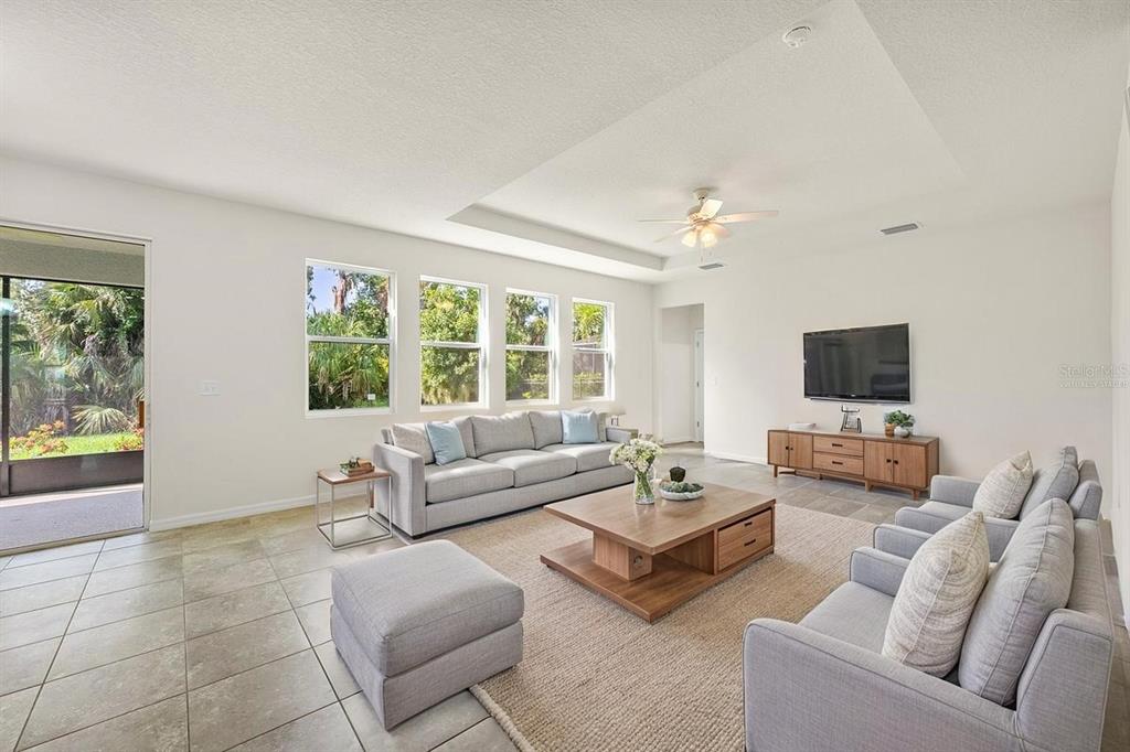 A bright living room features light tile floors, a tray ceiling, and two gray sofas — 5715 HEVENA COURT, PALMETTO, FL