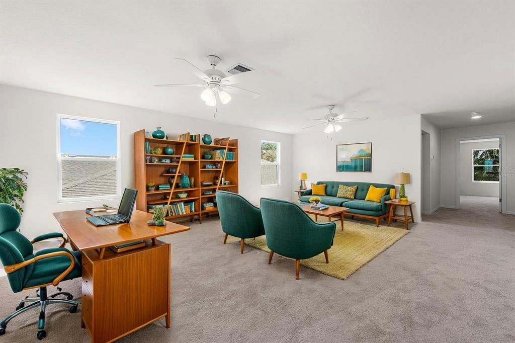A spacious living room with a desk, bookshelf, teal furniture, and two ceiling fans — 5715 HEVENA COURT, PALMETTO, FL