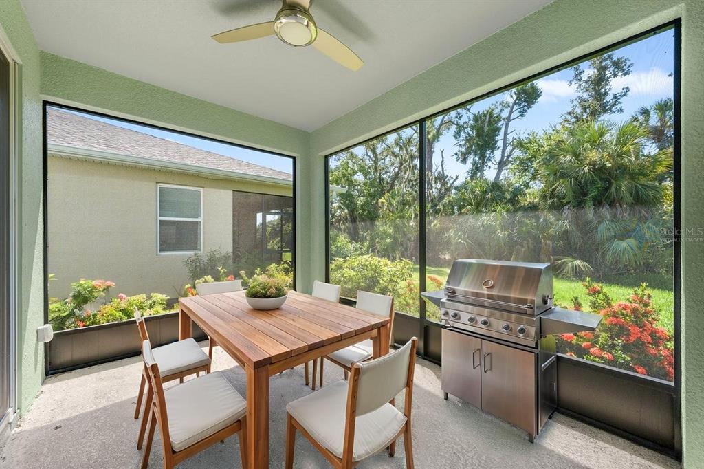 A screened-in patio features a wooden dining table, chairs, and a stainless steel grill — 5715 HEVENA COURT, PALMETTO, FL