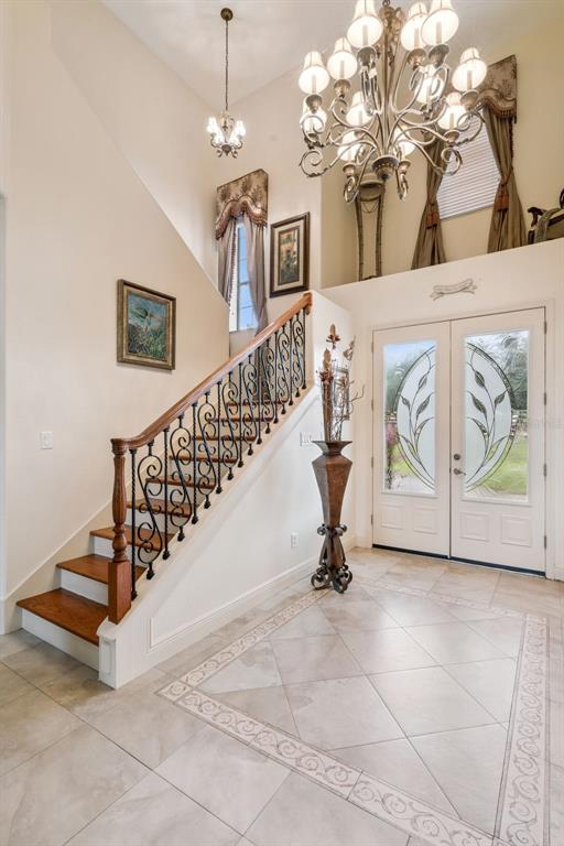 An entryway features a grand staircase with wrought iron railings, a chandelier, and tiled flooring — 19949 S BUCKHILL ROAD, CLERMONT, FL