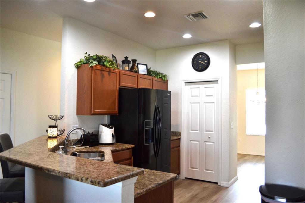 A kitchen features granite countertops, dark wood cabinets, a black refrigerator, and a white door — 2828 BLACKWATER CREEK DRIVE, LAKELAND, FL