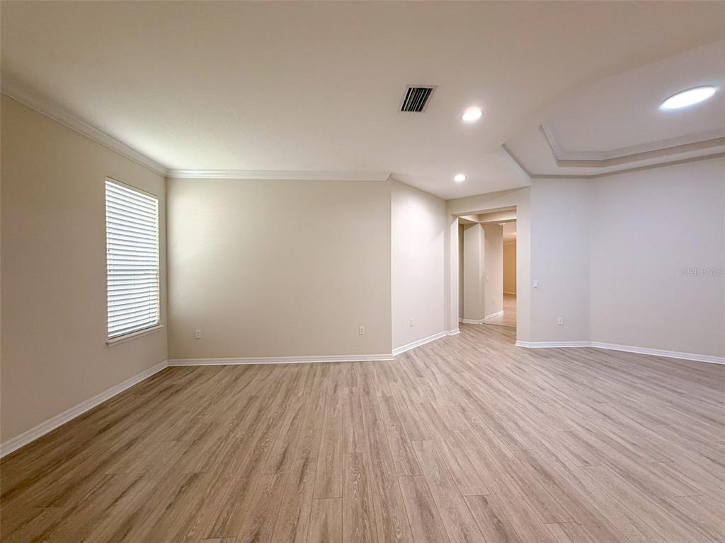 An empty room features light-colored walls, wood-look flooring, a tray ceiling, and a window — 12947 RUNSWICK AVENUE, WINDERMERE, FL