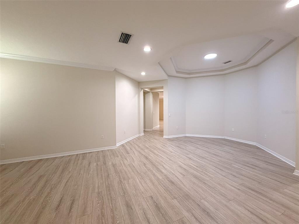 An empty room with light-colored walls, wood-look flooring, and a tray ceiling — 12947 RUNSWICK AVENUE, WINDERMERE, FL