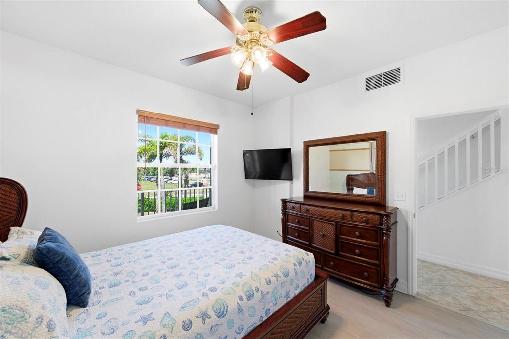 A bedroom features a bed with a seashell-patterned quilt, a wooden dresser, and a ceiling fan — 601 BAHIA BEACH BOULEVARD, RUSKIN, FL