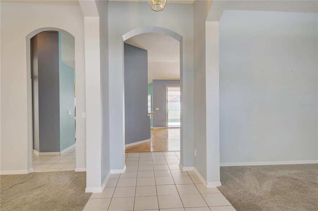 A tiled entryway leads through arched openings into a living area with wood flooring — 2688 SUGAR PINE RUN, OVIEDO, FL
