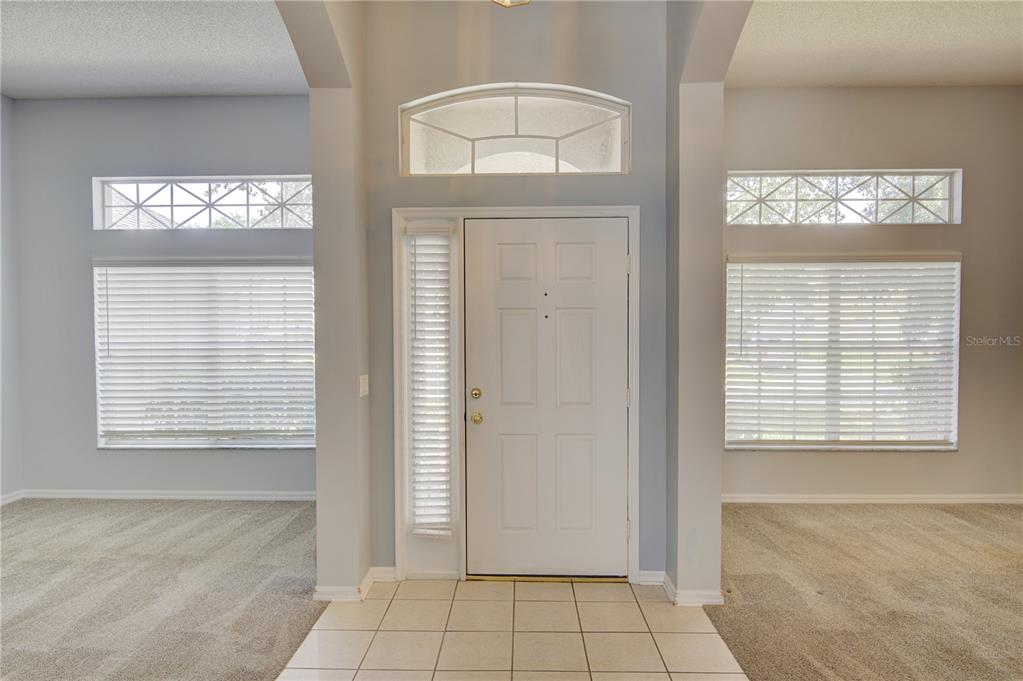 A tiled entryway leads to a white front door flanked by windows with horizontal blinds — 2688 SUGAR PINE RUN, OVIEDO, FL
