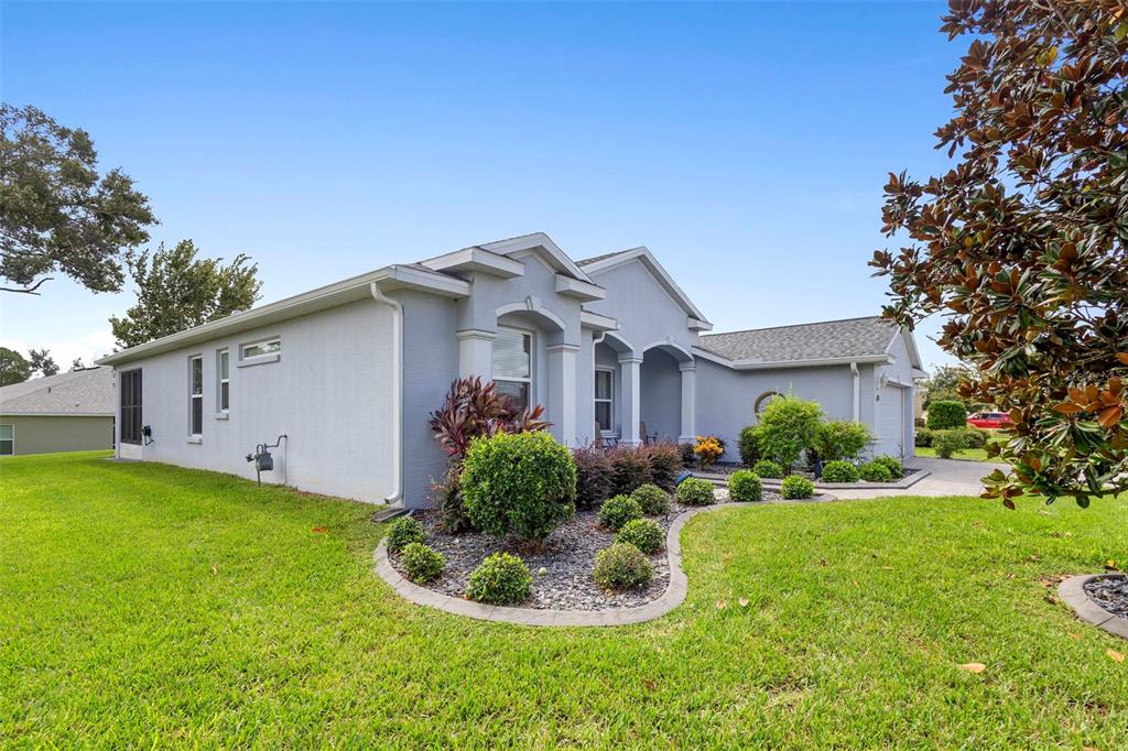 A single-story gray house with a landscaped front yard and a paved driveway — 27106 CAMERONS RUN, LEESBURG, FL