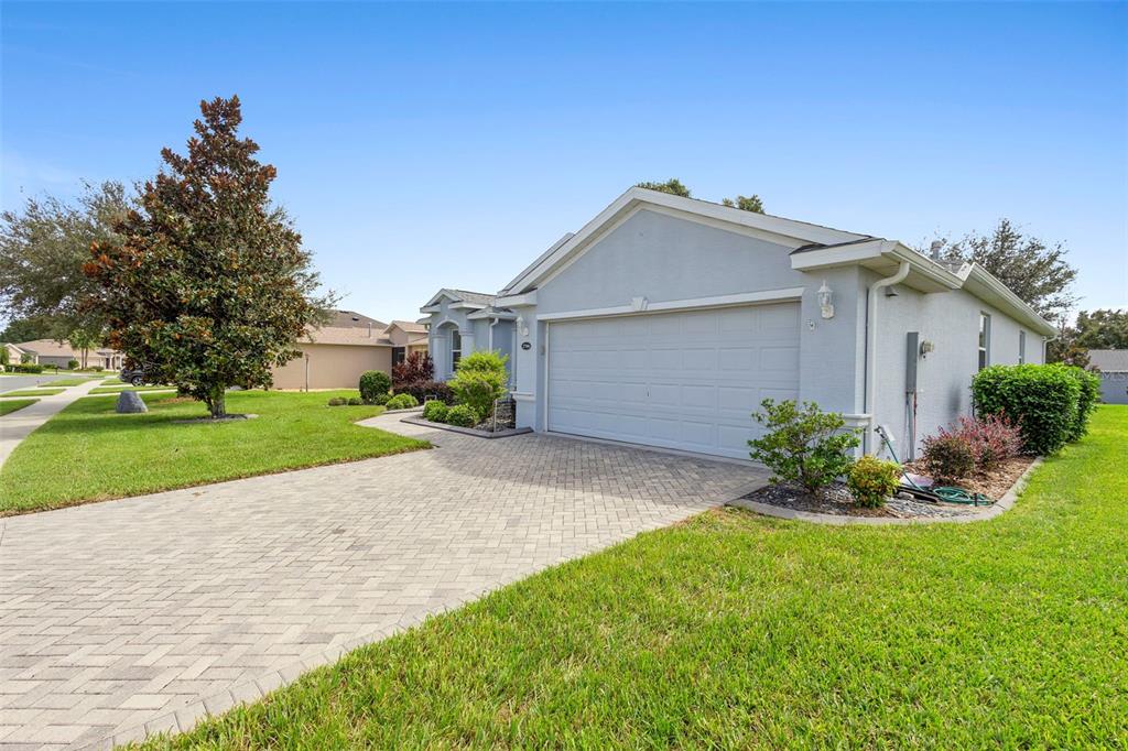 A light-colored single-story house features a two-car garage and a paved driveway — 27106 CAMERONS RUN, LEESBURG, FL