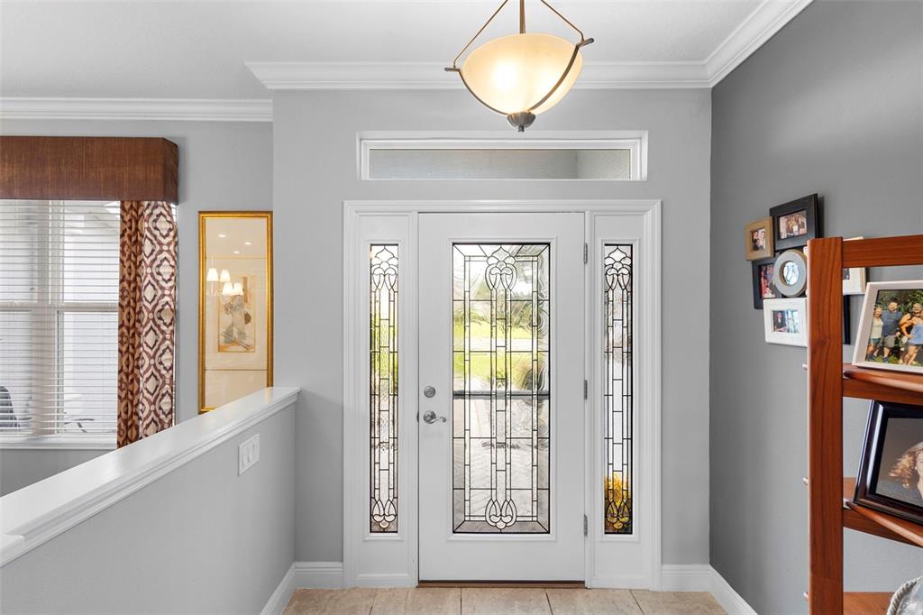 An entryway features a white front door with decorative glass panels and a transom window — 27106 CAMERONS RUN, LEESBURG, FL