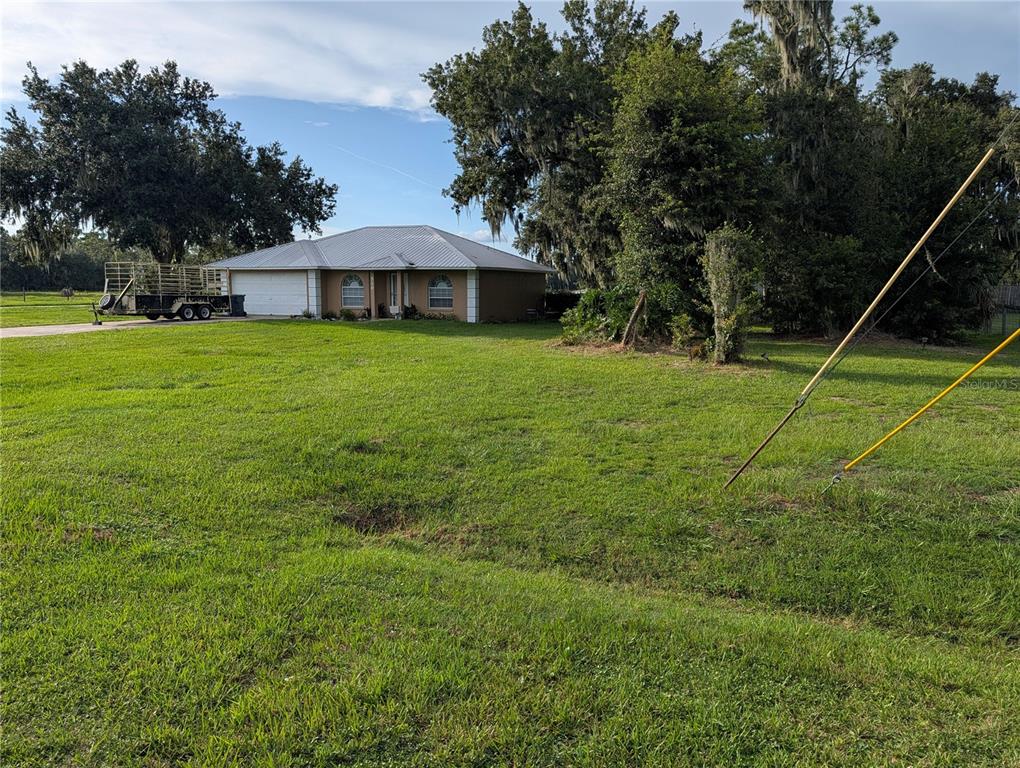 A single-story house with a metal roof sits on a large, grassy lot with trees — 510 CLOVERLEAF DRIVE, LITHIA, FL
