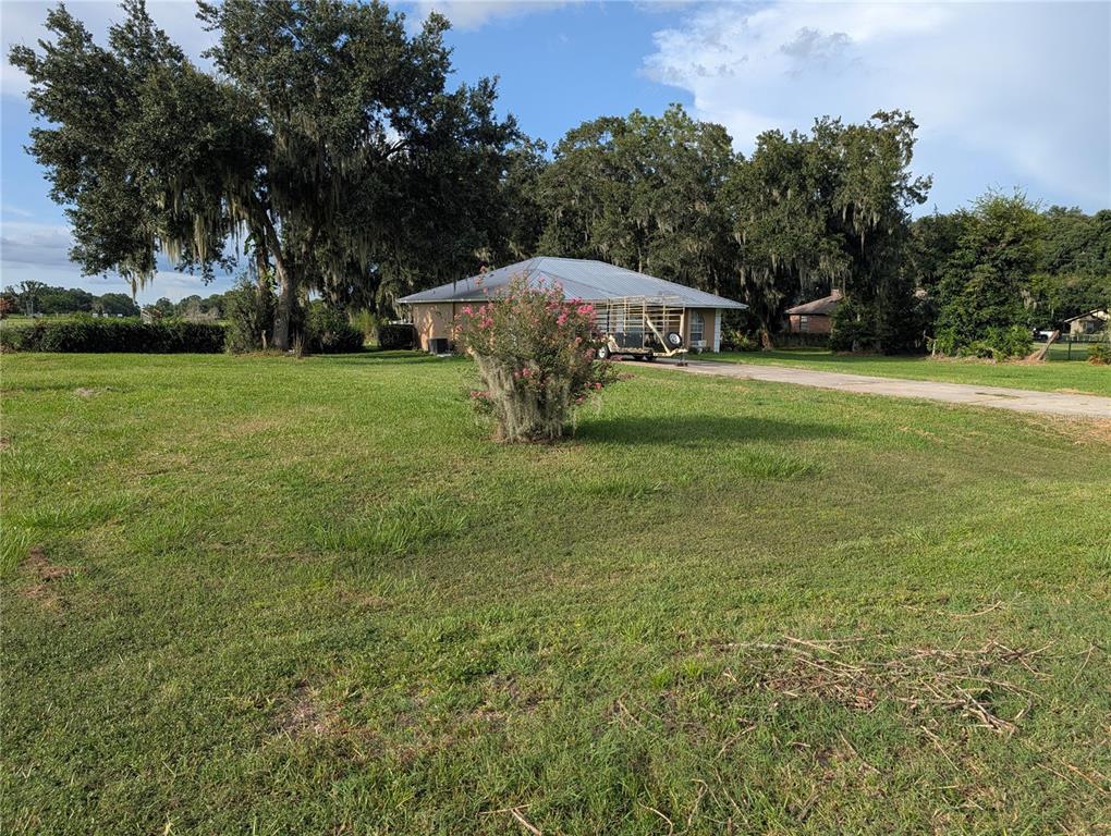 A single-story house with a metal roof sits on a large, grassy lot with trees — 510 CLOVERLEAF DRIVE, LITHIA, FL