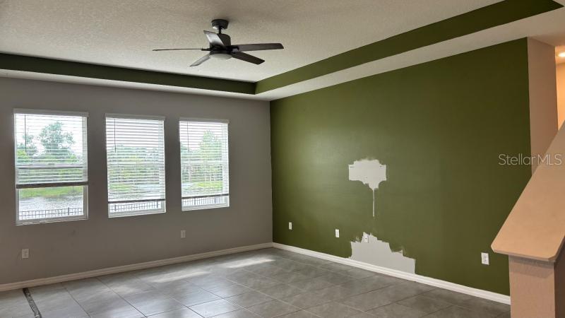 A living room features a green accent wall with paint damage, tile flooring, and windows — 16453 WOODSIDE GLEN, PARRISH, FL