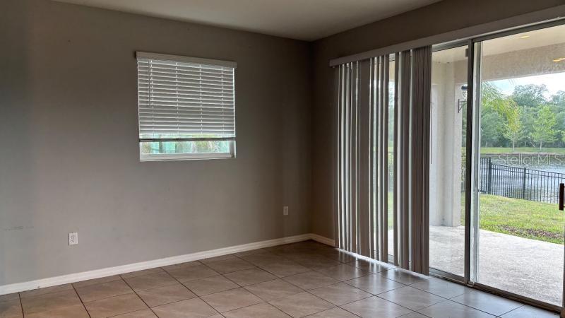 An empty room with tile flooring, a window with blinds, and sliding glass doors to a patio — 16453 WOODSIDE GLEN, PARRISH, FL