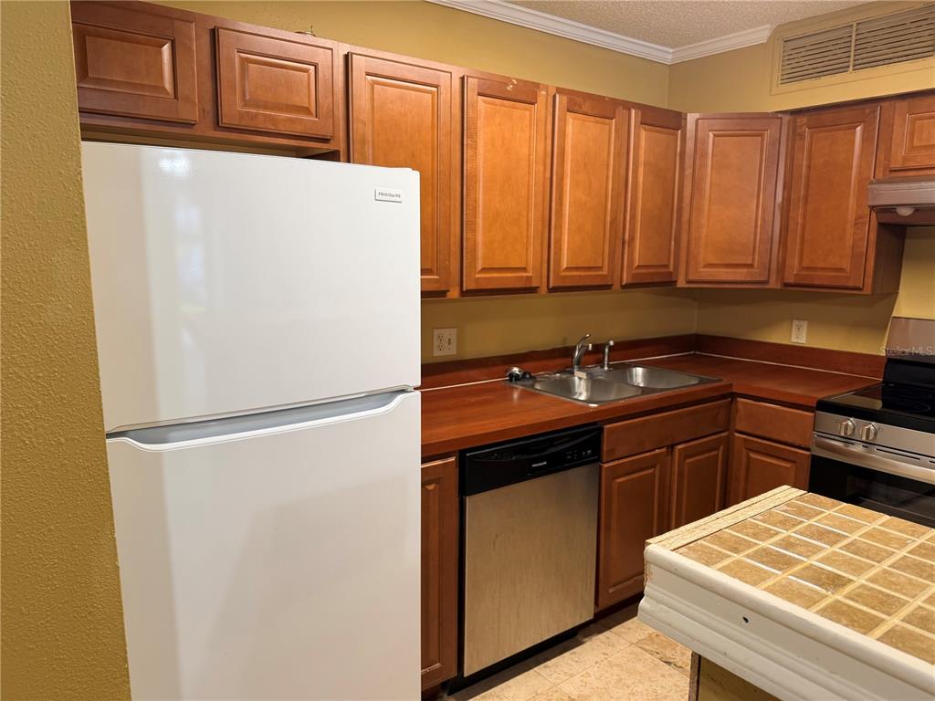 A kitchen features wood cabinets, a white refrigerator, a stainless steel dishwasher, and wood countertops — 345 FORESTWAY CIRCLE UNIT 107, ALTAMONTE SPRINGS, FL