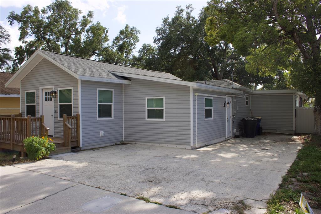 A gray-sided house features a wooden front deck, a white door, and a concrete driveway — 1574 EWING AVENUE, CLEARWATER, FL