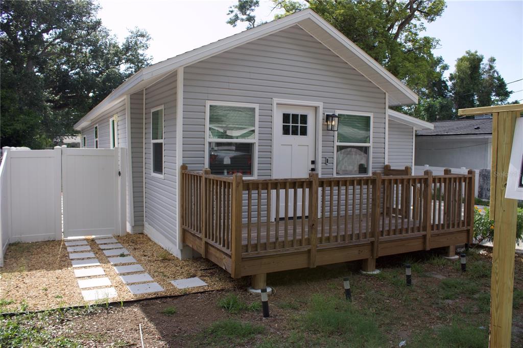 A small, light gray house with a wooden deck and a white vinyl privacy fence — 1574 EWING AVENUE, CLEARWATER, FL