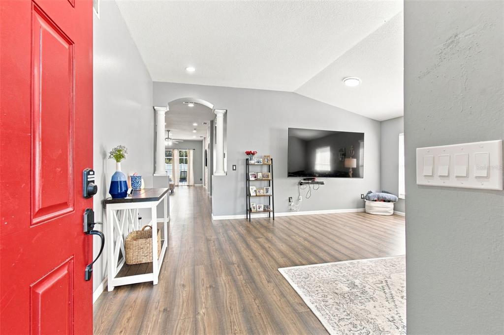 An entryway with a red door leads into a living room with wood-look flooring — 9710 WHITE BARN WAY, RIVERVIEW, FL