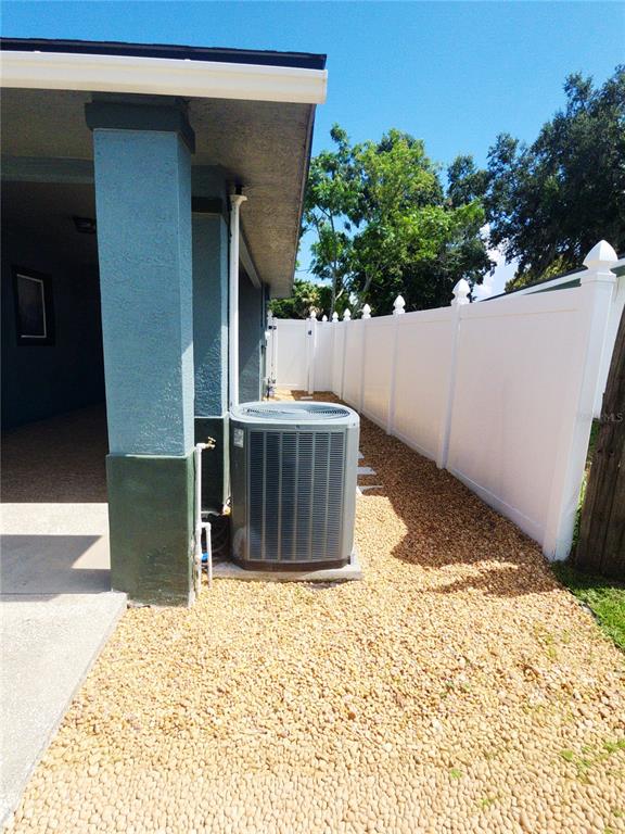 An outdoor air conditioning unit sits on a gravel side yard next to a white fence — 1337 LEE COURT, LEESBURG, FL