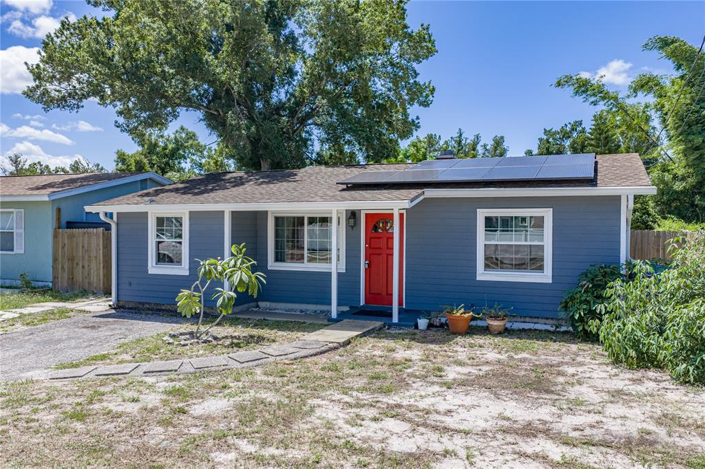 A single-story blue house with a red front door, solar panels, and a gravel driveway — 5326 6TH AVENUE S, ST PETERSBURG, FL