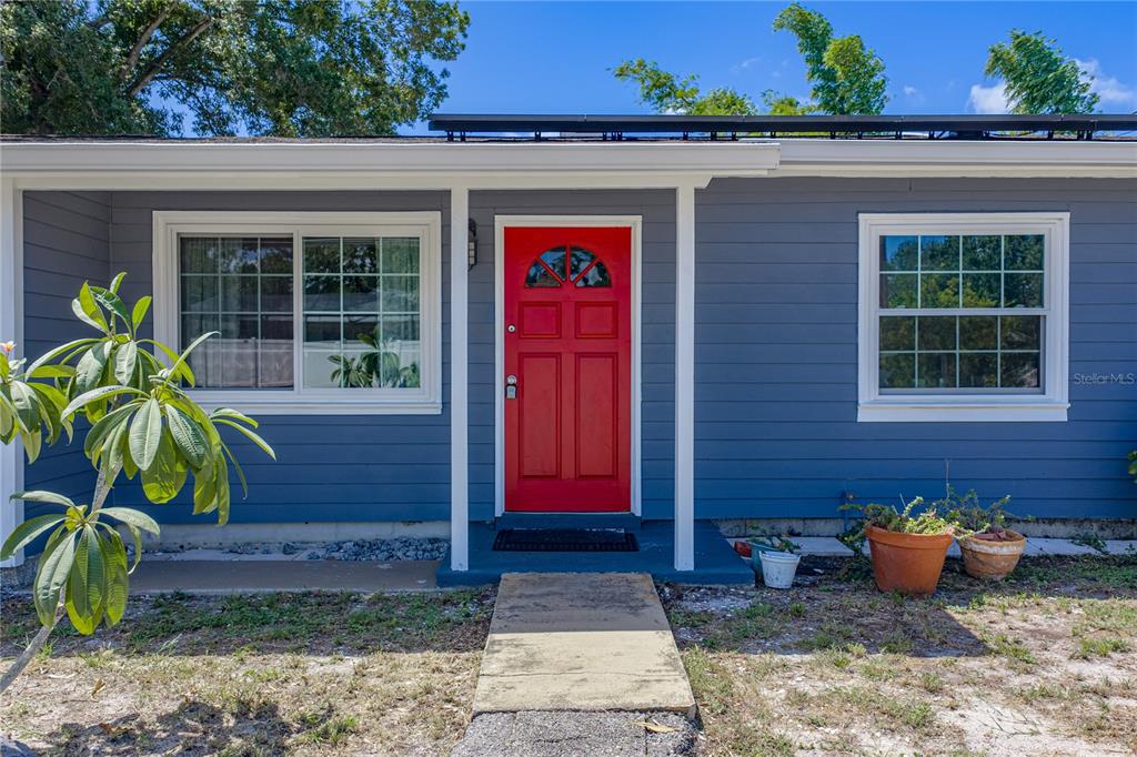 The exterior of a blue house features a bright red front door and two windows — 5326 6TH AVENUE S, ST PETERSBURG, FL