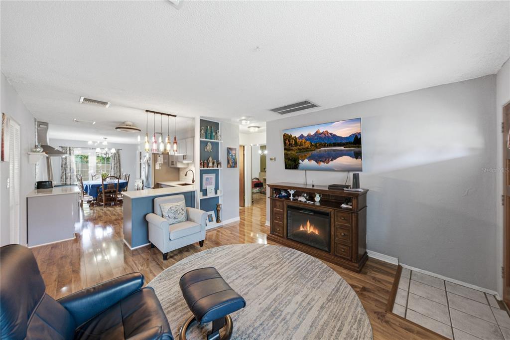 A living room with a fireplace console, television, and an open view into the kitchen — 5326 6TH AVENUE S, ST PETERSBURG, FL