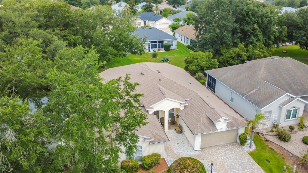 An aerial view shows a suburban house with a tan roof and paved driveway — 25243 RIVER CREST DRIVE, LEESBURG, FL