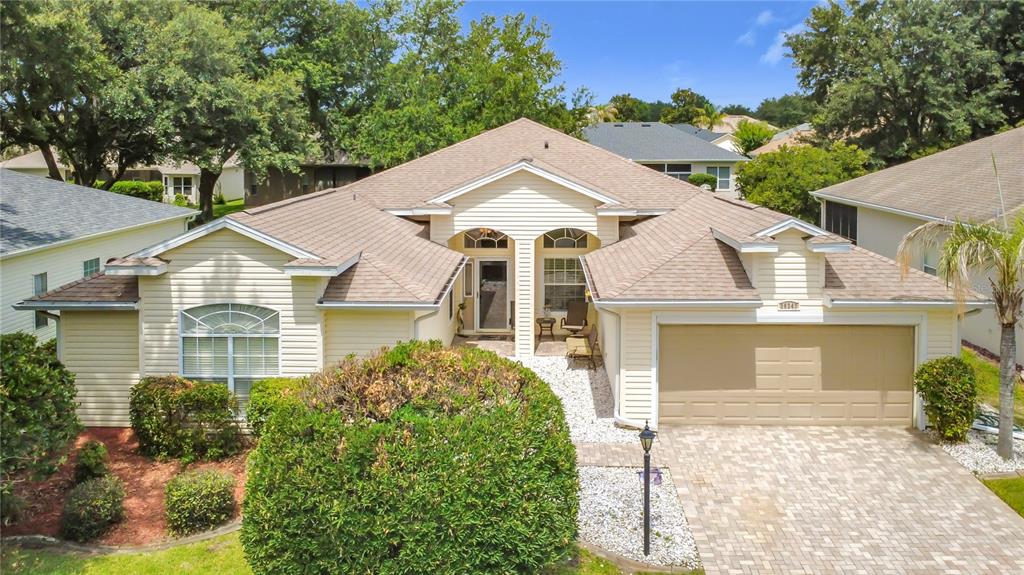 A single-story house with beige siding, a tan shingled roof, and a paved driveway — 25243 RIVER CREST DRIVE, LEESBURG, FL