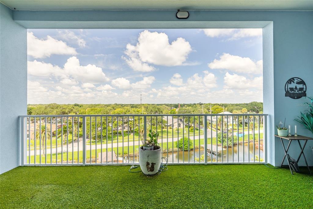 A balcony with artificial turf flooring overlooks a suburban landscape and a small body of water — 3 RIVERWALK DRIVE UNIT 602, NEW SMYRNA BEACH, FL
