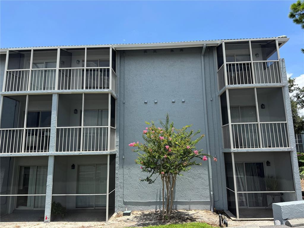 A three-story apartment building exterior features screened balconies and a small flowering tree in front — 115 OYSTER BAY CIRCLE UNIT 300, ALTAMONTE SPRINGS, FL