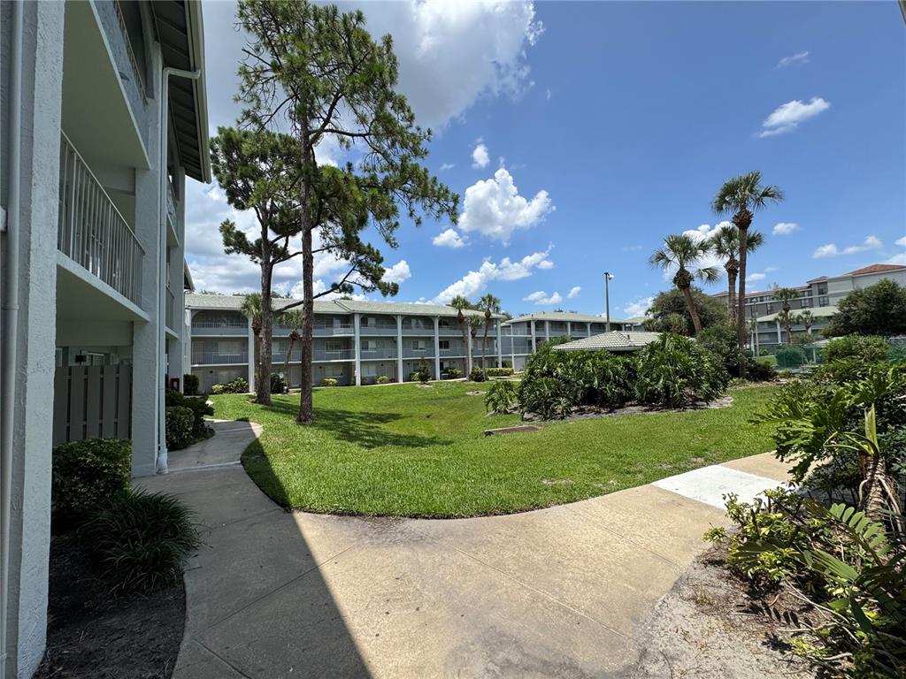 A view of a grassy courtyard between multi-story apartment buildings with palm trees and walkways — 115 OYSTER BAY CIRCLE UNIT 300, ALTAMONTE SPRINGS, FL