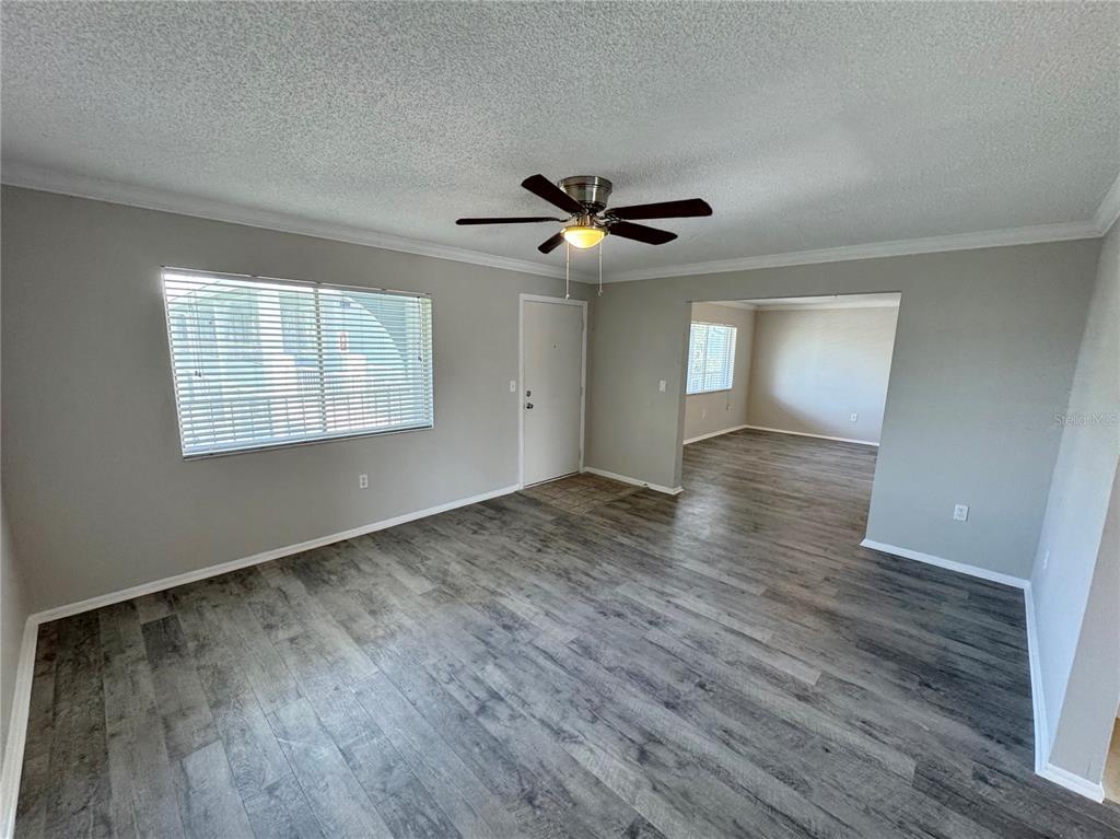 A living room with gray walls, wood-look flooring, a ceiling fan, and an adjacent room — 115 OYSTER BAY CIRCLE UNIT 300, ALTAMONTE SPRINGS, FL